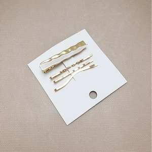 Detail view of 4-piece golden minimalist hair clip set on a white display card