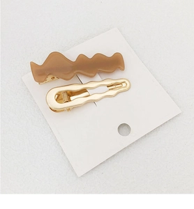 Detail of wavy hair clip set featuring brown resin and gold metal on a white card