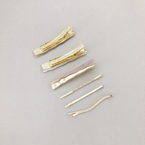 6-piece minimalist gold hair clip set with purple resin accent on grey background