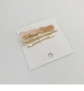 Detailed set of wavy acetate hair clip and gold metallic twist bobby pins on card