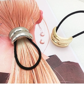 Detail of minimalist metallic U-shaped hair tie in polished gold and silver finish