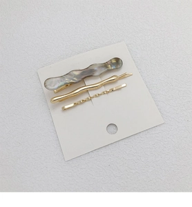 Close-up of three-piece set with gray wave acetate clip and golden metal hairpins