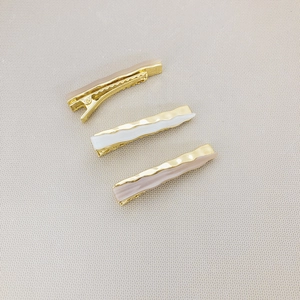 Three-piece set of wave-shaped hair clips in cream, coffee, and pink with gold metal base