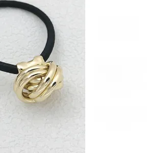Detailed close-up of a gold knotted metal ornament on a high-elastic black hair tie
