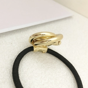 Detail view of interlocking gold metal rings on a durable black elastic hair tie