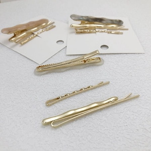 Set of minimalist golden alloy hair clips with marble resin accents on white surface