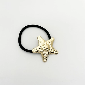Close-up of golden starfish hair tie with textured finish on black elastic band