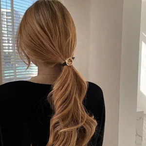 Minimalist gold metal spiral hair tie with black elastic rope for elegant ponytail look