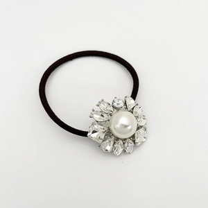 Détail d'un élastique à cheveux fleuri orné de strass et d'une perle blanche centrale