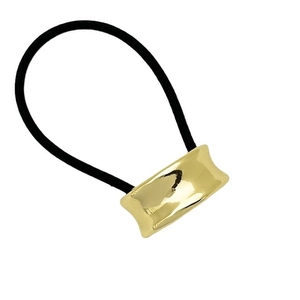 Minimalist elastic hair tie with polished gold U-shaped metal tube on white background