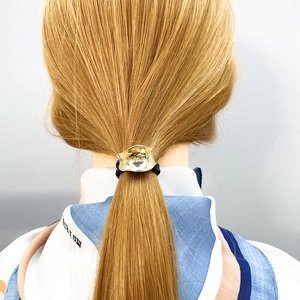 Dettaglio del fermacoda concavo dorato con elastico nero ad alta elasticità per capelli
