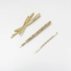 Detailed view of three gold alloy hair pins with pearls and hammered textures