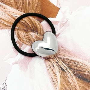 Close-up of a silver mirror heart pendant on high-elasticity black hair tie band