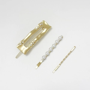 Détail d'un lot de 3 barrettes dorées avec perles et strass sur fond blanc épuré