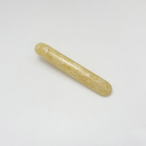 Macro detail of amber marbled resin hair clip with elegant cream finish on white background