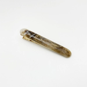 Detail of resin hair clip with brown marble pattern and golden metal base