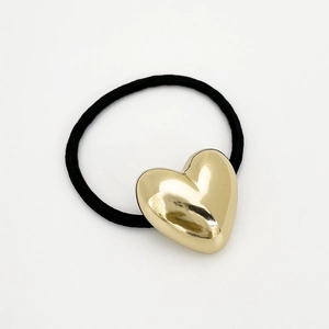 Detail of high-elastic black hair tie featuring a polished 3D gold heart ornament