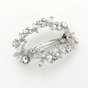 Détail d'une barrette fleurie argentée ornée de perles blanches et strass brillants