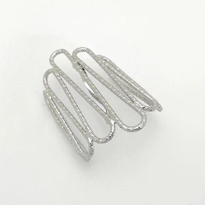 Macro detail of silver minimalist ring with hammered texture and wavy multi-layer curves