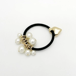 Détail d'un élastique à cheveux avec perles blanches et pendentif en forme de cœur doré