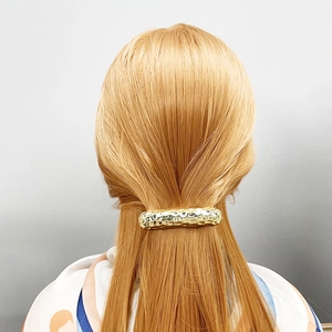 Gold textured metal hair clip in a minimalist style on a woman's long hair