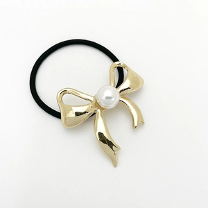 Detailed view of elegant black elastic hair tie with gold bow and pearl accent