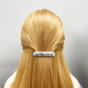 Detail of silver alloy hair clip with hammer texture on blonde hair for women