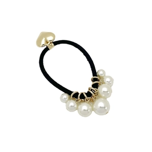 Élastique cheveux noir avec pendentif cœur doré et perles blanches sur fond blanc neutre