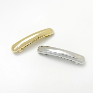 Close-up of set of two minimalist curved hair clips in polished gold and silver finish