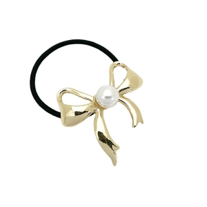 Elastic hair tie with golden metal bow and white pearl accent on a minimalist white background