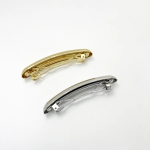 Close-up of gold and silver metallic spring hair clips with a polished mirror finish