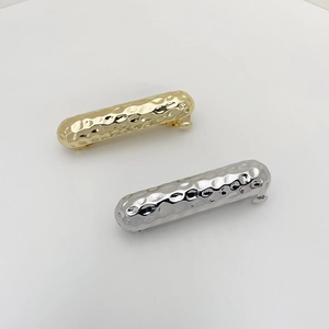 Close-up of gold and silver hammered metal spring hair clips on white background