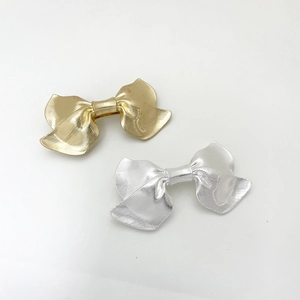 Detail of metallic bow hair clips showing textured striped finish in gold and silver