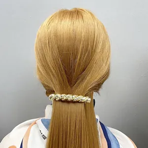 Fermaglio per capelli in metallo dorato a corda con trama a martello su coda bionda