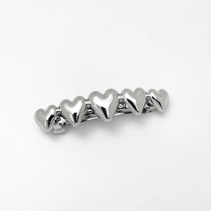 Detailed macro view of the silver metallic heart-shaped spring hair clip with mirror finish