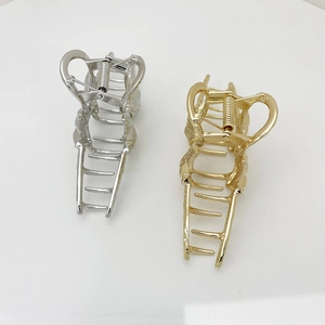 Detail view of large gold and silver alloy claw clips with polished finish and sturdy spring