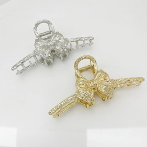 Detail view of large metal bow hair claws in gold and silver finish with spring clips
