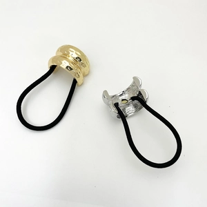 Dettaglio dei polsini in metallo martellato oro e argento su elastici per capelli chic