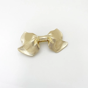 Detailed view of the gold alloy bow hair clip featuring a fine horizontal brushed texture