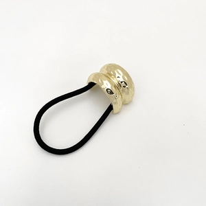 Dettaglio dell'anello per capelli in metallo martellato dorato con elastico nero