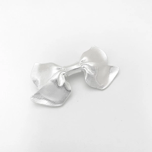 Detailed macro shot of a silver alloy bow hair clip with textured striped metallic finish