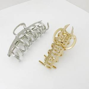 Detail view of large alloy hair claws in gold and silver with hammered texture