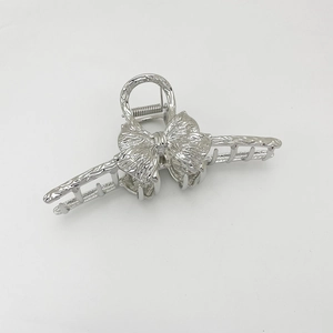 Macro view of silver alloy hair claw clip with hammered texture and bow design