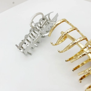 Detailed macro of large metal hair claws featuring hammered texture in gold and silver