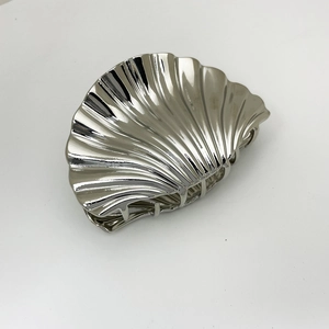 Macro view of silver shell hair claw clip with polished metallic finish and teeth detail