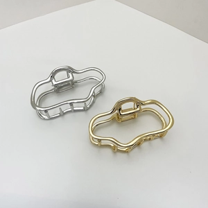 Macro detail of wave-shaped hollow metal hair claws in glossy gold and silver plating