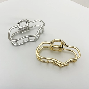 Detail of large cloud-shaped metal hair claws in gold and silver with mirror finish