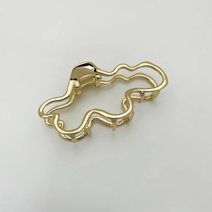 Detailansicht der goldenen Haarklammer in unregelmäßiger Wellenform mit Glanzfinish