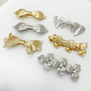 Detail of silver and gold alloy hair clips featuring bow and floral designs with rhinestones
