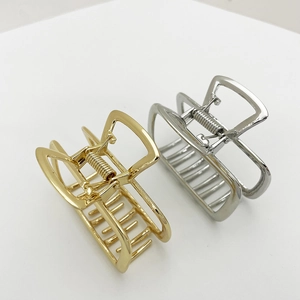 Macro detail of square hollow metal hair claw clips in polished gold and silver finishes